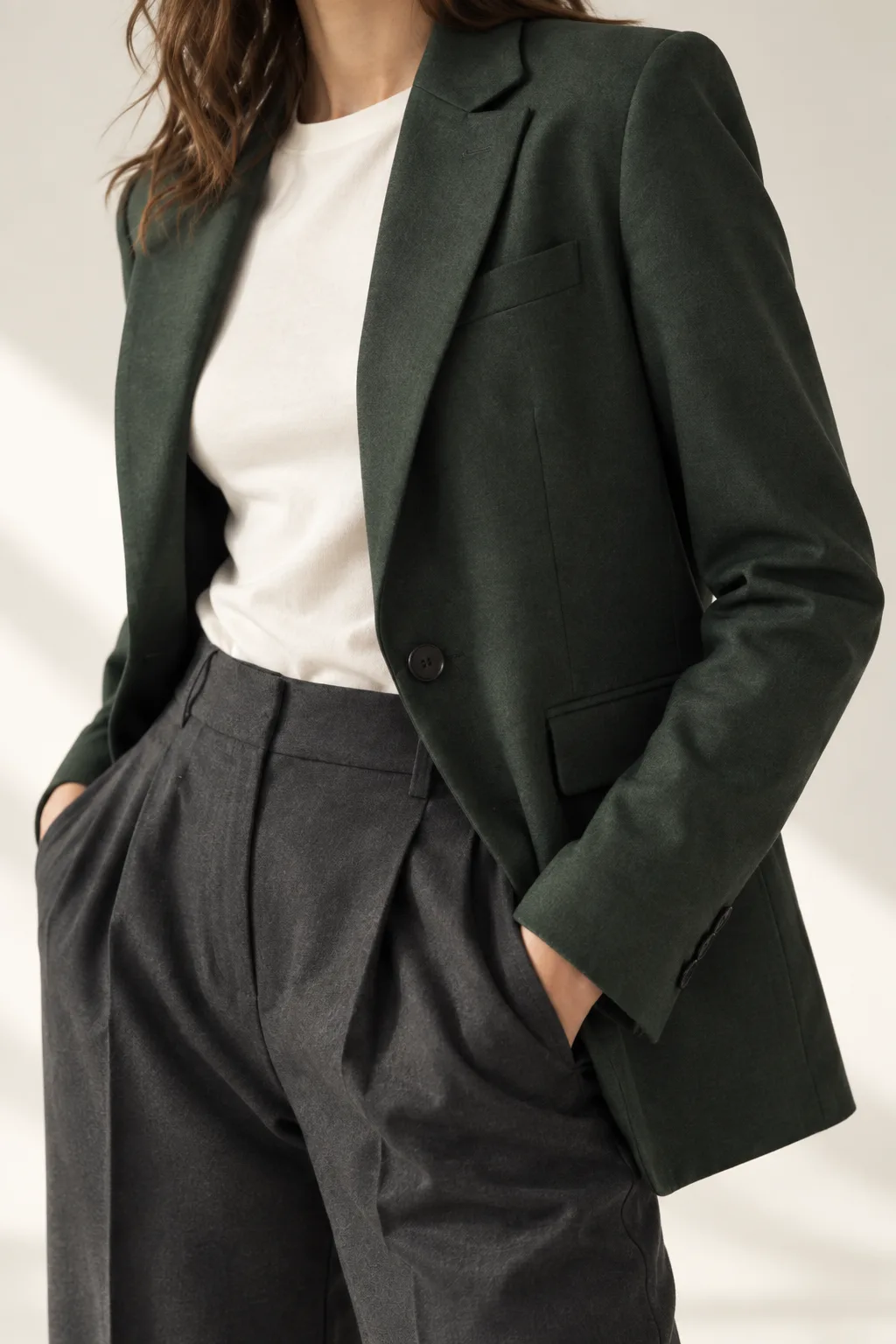 AI-generated close crop of the fictional green blazer, lapel and pocket; not a verified photograph of a physical garment